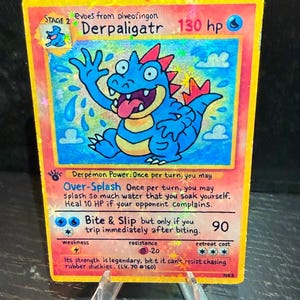 May include: A holographic trading card featuring a blue Derpaligatr character with red accents, tongue out, and the text "Derpaligatr 130 hp." The card has a yellow border and includes game instructions and a weakness symbol.
