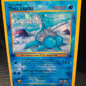May include: A Thicc Lapras Pokémon trading card with a blue and white design. The card features the text "Thicc Lapras" and "80 HP". The card has a holographic background and a yellow border.