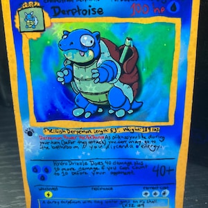 May include: A blue and yellow Derptoise trading card. The card features a cartoon turtle-like creature with the text "Derptoise" and "100 hp". The card also includes text describing the creature's abilities and stats, including a length of 5'3" and a weight of 189 lbs.