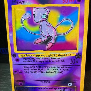 May include: A custom-painted trading card featuring a cartoon Mew character in shades of purple and pink. The card includes handwritten text with the phrase "Say FUCK THAT EVOLUTION!" and other details. The card is approximately 1 foot 4 inches in length and weighs 9 pounds.