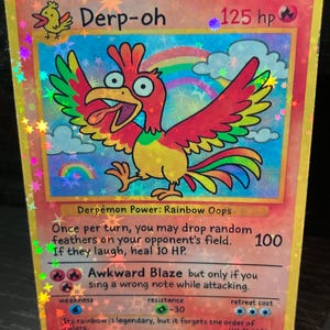 May include: A holographic trading card featuring a cartoon bird character named "Derp-oh." The card has a rainbow and cloud background, with text indicating its HP and special abilities. The card is displayed on a clear stand.