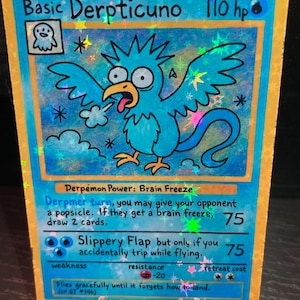 May include: A holographic trading card featuring a cartoon bird character named "Basic Derpticuno." The card has a blue background with the character in the center, and text describing its powers and abilities. The card is displayed on a clear stand.