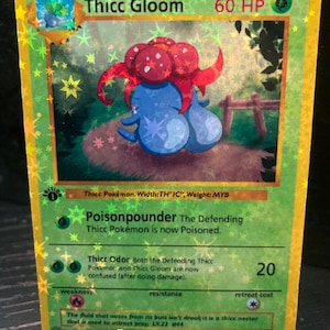 Könnte beinhalten: Holografische Pokémon-Karte mit "Thicc Gloom". Die Karte hat einen grünen Hintergrund mit einer Cartoon-Illustration einer blauen Kreatur mit roten und weißen Akzenten. Text: "Poisonpounder" und "Thicc Odor".