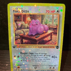 Könnte beinhalten: Eine holografische Sammelkarte mit einer violetten, blob-artigen Kreatur namens Thicc Ditto mit 70 KP. Die Illustration zeigt die Kreatur auf einem hölzernen Couchtisch in einem Wohnzimmer. Die Karte enthält Text zur Deeper Copy Attacke.
