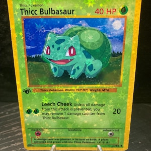 Könnte beinhalten: Eine holografische Sammelkarte mit einem Cartoon-Bulbasaur-Charakter. Die Karte hat einen grünen und goldenen Rand mit dem Text "Thicc Bulbasaur" und "40 HP". Die Karte enthält auch den Text "Leech Cheek" und "20".