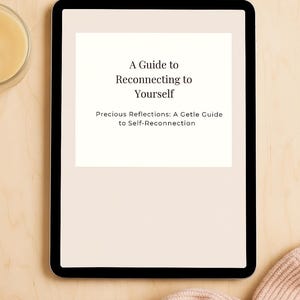 May include: A digital tablet displays the text "A Guide to Reconnecting to Yourself" on a white background. The tablet is on a light wood surface, with a soft pink knitted item and a small glass container visible.