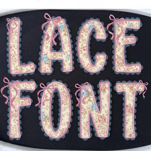 Puede incluir: Sobre un fondo negro, la inscripción "LACE FONT" presenta un diseño floral. Cada letra está bordeada con encaje rosa y adornada con un lazo rosa. El patrón floral incluye flores rosas y azules.