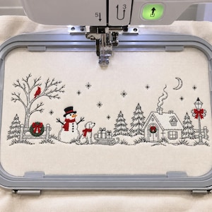 Pode incluir: Um bastidor de bordado com tecido off-white e uma cena de inverno em arte linear preta, apresentando um boneco de neve, um cão, uma casa, pinheiros, uma lua crescente e estrelas. Detalhes vermelhos destacam um cardeal, cachecóis, guirlandas e um laço num poste de luz.