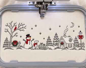 Pode incluir: Um bastidor de bordado com tecido off-white e uma cena de inverno em arte linear preta, apresentando um boneco de neve, um cão, uma casa, pinheiros, uma lua crescente e estrelas. Detalhes vermelhos destacam um cardeal, cachecóis, guirlandas e um laço num poste de luz.