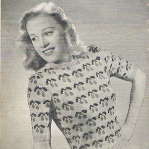 May include: A black and white photo of a woman wearing a knitted sweater with a cherry fair isle pattern. The sweater is made with 5 ounces of 3-ply yarn in the main color, 2 ounces of green yarn, and 1 ounce of red yarn. The pattern is called "Cherry Fair Isle" and the leaflet number is 616.