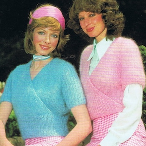 May include: Two women wearing fuzzy knit sweaters with a wrap style neckline. The woman on the left is wearing a light blue sweater and a pink headband. The woman on the right is wearing a pink sweater and a white collared shirt. Both women are wearing pink and white gingham skirts.