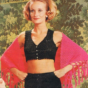 May include: A woman wearing a black crocheted crop top with white buttons and a pink crocheted shawl with fringe. The shawl is draped over her shoulders and has a long fringe.