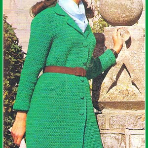 Könnte beinhalten: Ein grüner Häkelmantel mit einem braunen Gürtel und einem blauen Schal. Der Mantel hat einen Knopfverschluss und einen langen, fließenden Stil.
