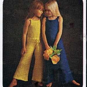 May include: Two girls wearing crocheted dresses, one yellow and one blue, stand side by side holding a bouquet of yellow flowers.