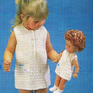 May include: A white knitted sleeveless dress with a button closure and a pocket on the front. A doll wearing a similar white knitted dress is being held by a young girl.