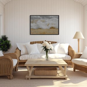 May include: A coastal-themed living room with wicker furniture, including a sofa, two armchairs, and a coffee table. A framed picture of ocean waves hangs above the sofa. White cushions and a vase of white flowers add to the room's bright, airy feel. A small green plant is in the corner.