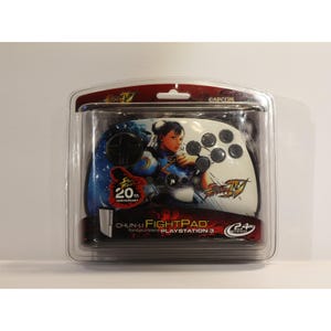 May include: A white and blue Chun-Li FightPad for PlayStation 3, packaged in a clear plastic case. The controller features a portrait of Chun-Li and the text "20th Anniversary".