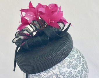 Black pillbox in straw with fuchsia feather "flowers" and sinamay twists