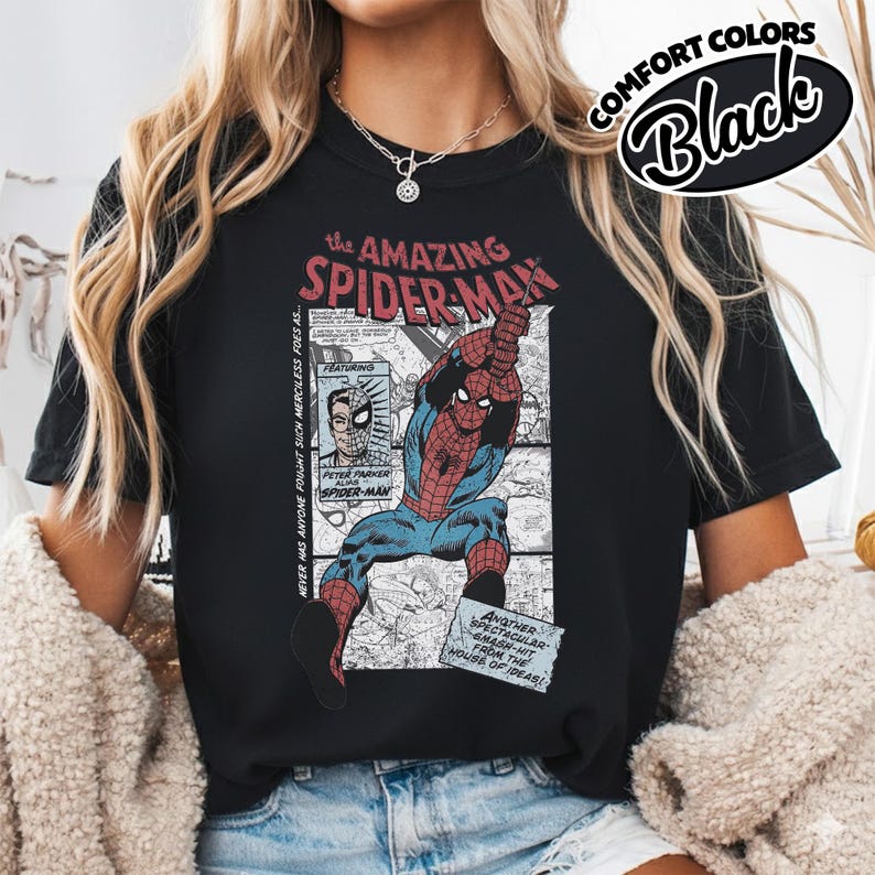K&ouml;nnte beinhalten: Schwarzes T-Shirt mit einer Vintage-Comic-Illustration von Spider-Man. Die Grafik enth&auml;lt den Text "the AMAZING SPIDER-MAN" und "COMFORT COLORS Black". Der Superheld ist in seinem klassischen rot-blauen Anzug dargestellt.