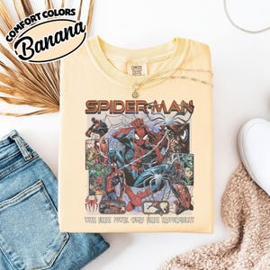 K&ouml;nnte beinhalten: Ein hellgelbes T-Shirt mit einem Spider-Man-Motiv. Die Grafik zeigt das Wort "Spider-Man" in Rot und eine Collage von Spider-Man-Illustrationen. Der Text "WITH GREAT POWER COMES GREAT RESPONSIBILITY" ist ebenfalls sichtbar.