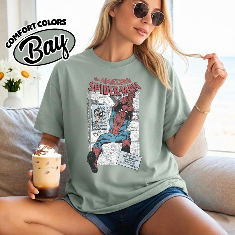 K&ouml;nnte beinhalten: Hellgr&uuml;nes Comfort Colors T-Shirt mit einem Vintage-Comic-Grafik von Spider-Man. Die Grafik enth&auml;lt den Text "The Amazing Spider-Man" und andere Comic-Elemente. Das Shirt hat eine entspannte Passform.