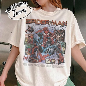 K&ouml;nnte beinhalten: Elfenbeinfarbenes T-Shirt mit einem Spider-Man-Motiv. Das Design enth&auml;lt das Wort "SPIDERMAN" in Rot und Braun, Comic-Panels und den Satz "WITH GREAT POWER COMES GREAT RESPONSIBILITY."