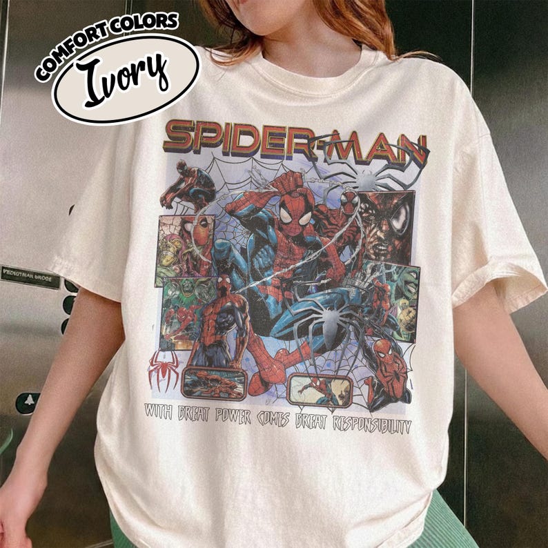 K&ouml;nnte beinhalten: Elfenbeinfarbenes T-Shirt mit einem Spider-Man-Motiv. Das Design enth&auml;lt das Wort "SPIDERMAN" in Rot und Braun, Comic-Panels und den Satz "WITH GREAT POWER COMES GREAT RESPONSIBILITY."