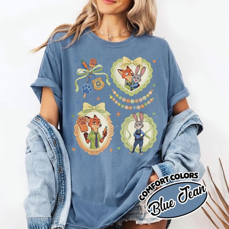 May include: A blue jean colored t-shirt featuring a graphic print of Zootopia characters Nick Wilde and Judy Hopps. The design includes four distinct sections with illustrations of the characters, a police badge, a popsicle, and bows.