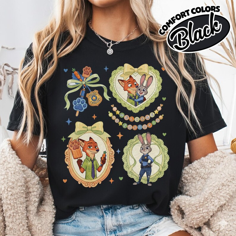 May include: A black t-shirt featuring a graphic print of Zootopia characters Nick Wilde and Judy Hopps. The design includes illustrations of the characters in ornate frames, a police badge, a paw-shaped popsicle, and the text Welcome to Zootopia.