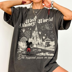 Peut inclure: T-shirt gris fonc&eacute; avec un motif vintage de Walt Disney World. Le design comprend le ch&acirc;teau Disney, Mickey Mouse et le texte "The happiest place on earth."