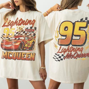 Puede incluir: Camiseta color crema con Lightning McQueen de la pel&iacute;cula Cars. La parte delantera muestra a McQueen con el texto "Lightning 95 McQueen". La parte trasera muestra un gran "95" con "Lightning McQueen" y una bandera a cuadros.