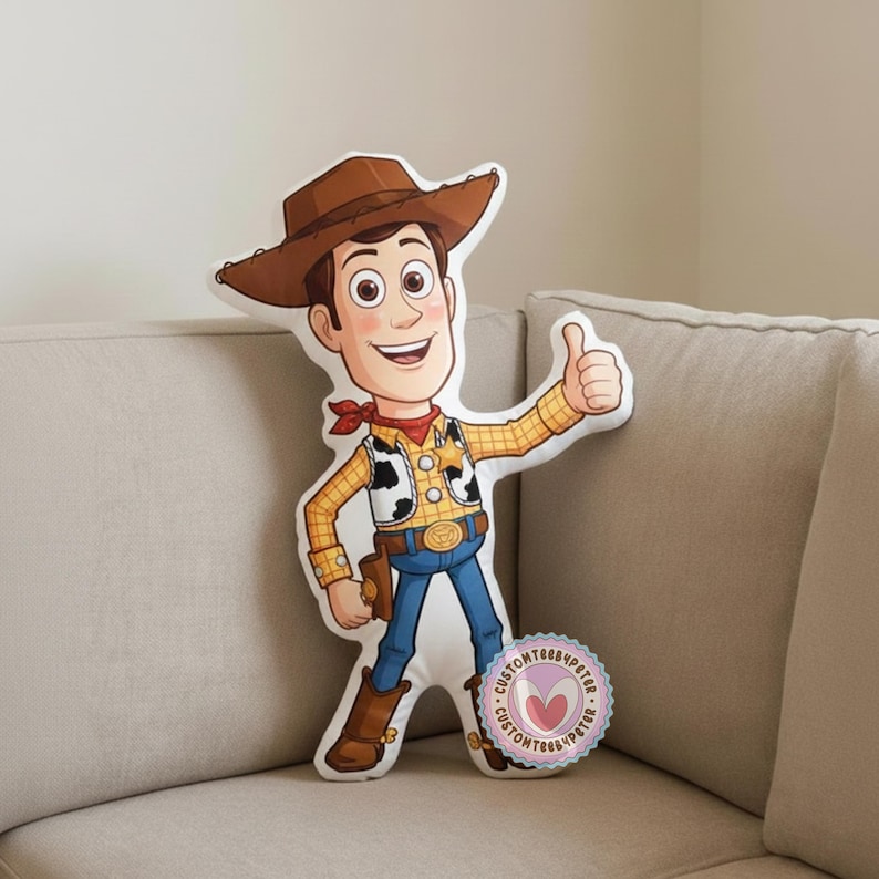 Peut inclure: Un coussin en forme du personnage Woody du film d'animation Toy Story. Woody porte un chapeau de cowboy marron, une chemise &agrave; carreaux jaune, un jean bleu et des bottes marron. Il fait un signe de pouce.