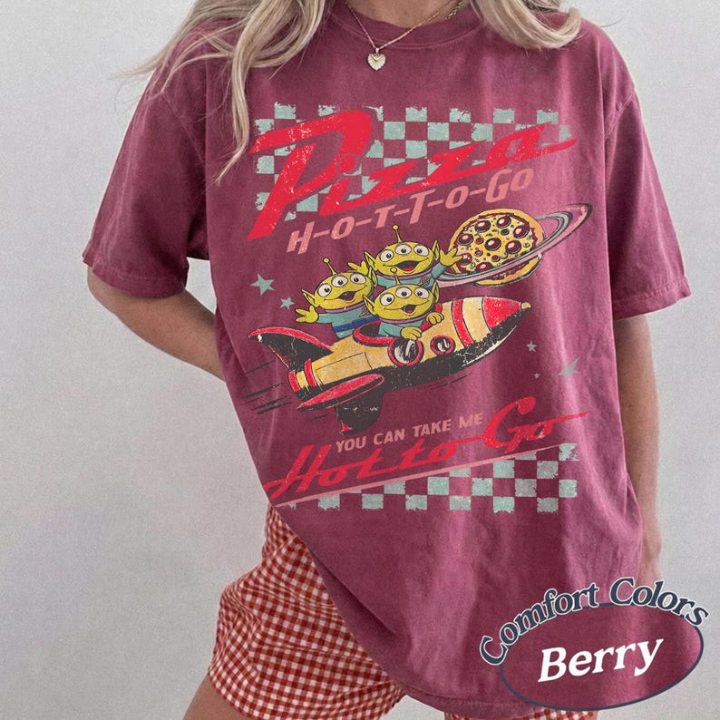 Pu&ograve; includere: T-shirt color bacca con grafica "Pizza H-O-T-T-O-Go" e un razzo che trasporta tre alieni verdi. Una pizza orbita un pianeta. La maglietta ha un aspetto vintage e usurato.