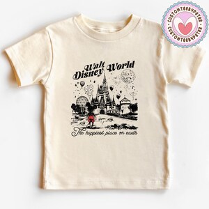 Peut inclure: T-shirt cr&egrave;me avec une illustration en noir et blanc de Walt Disney World. Le graphisme comprend Mickey Mouse, un ch&acirc;teau, des feux d'artifice et le texte "Walt Disney World" et "The happiest place on earth."