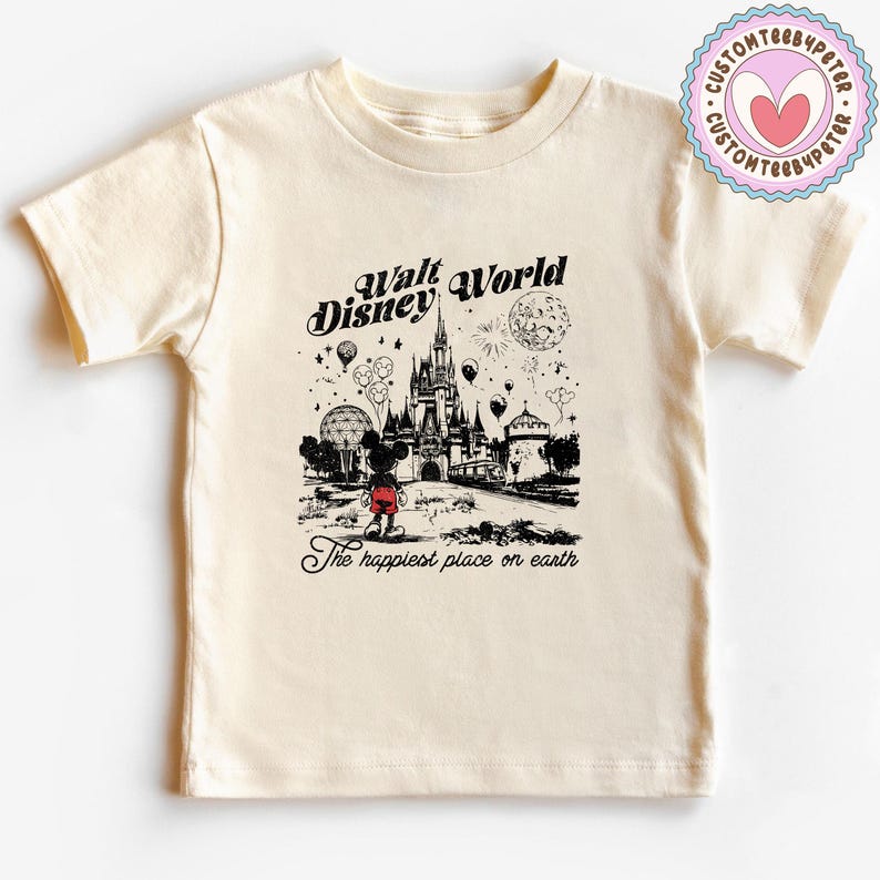 Peut inclure: T-shirt cr&egrave;me avec une illustration en noir et blanc de Walt Disney World. Le graphisme comprend Mickey Mouse, un ch&acirc;teau, des feux d'artifice et le texte "Walt Disney World" et "The happiest place on earth."