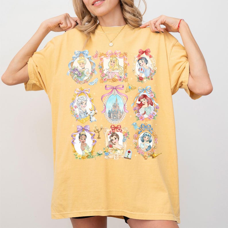 Pu&ograve; includere: T-shirt giallo senape con ritratti ad acquerello di principesse in cornici decorative. Ogni ritratto &egrave; circondato da fiocchi, fiori e farfalle. La maglietta ha una vestibilit&agrave; ampia e un girocollo.