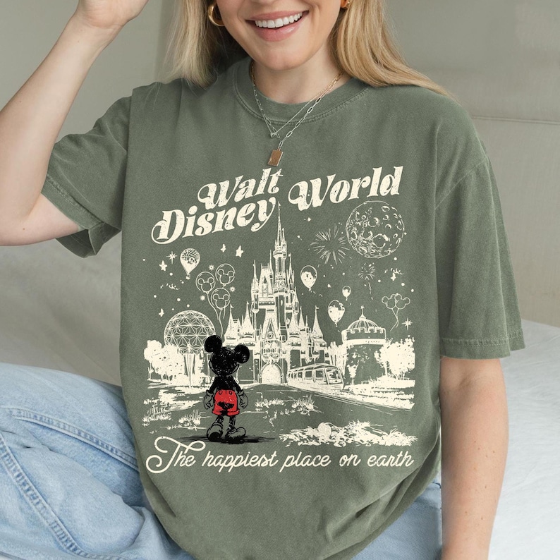 Peut inclure: T-shirt vert olive avec un dessin de Mickey Mouse devant le ch&acirc;teau de Cendrillon &agrave; Walt Disney World. Le texte indique "Walt Disney World" et "The happiest place on earth."