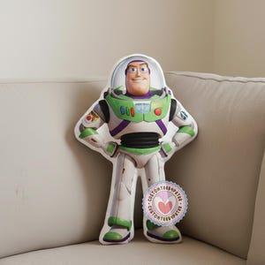 Peut inclure: Une peluche Buzz l'&Eacute;clair de la franchise Toy Story. Le jouet est blanc, vert et violet, avec un casque transparent et un visage souriant. Le jouet est debout, les mains sur les hanches. Un autocollant avec un c&oelig;ur est en bas.