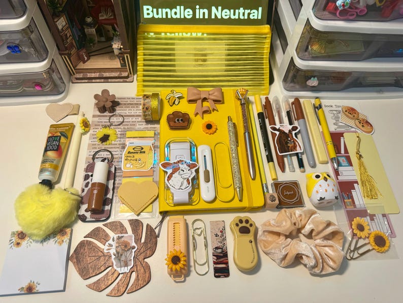May include: A collection of yellow-themed stationery and accessories including a yellow notebook, pens, markers, a yellow pencil case, sunflower-themed clips, a cow sticker, a plush heart keychain, a velvet scrunchie, and various decorative paper items.