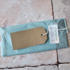 May include: A brown paper gift tag with the text "With Love from Sweet Pea Design" tied with twine to a light blue tissue paper package.