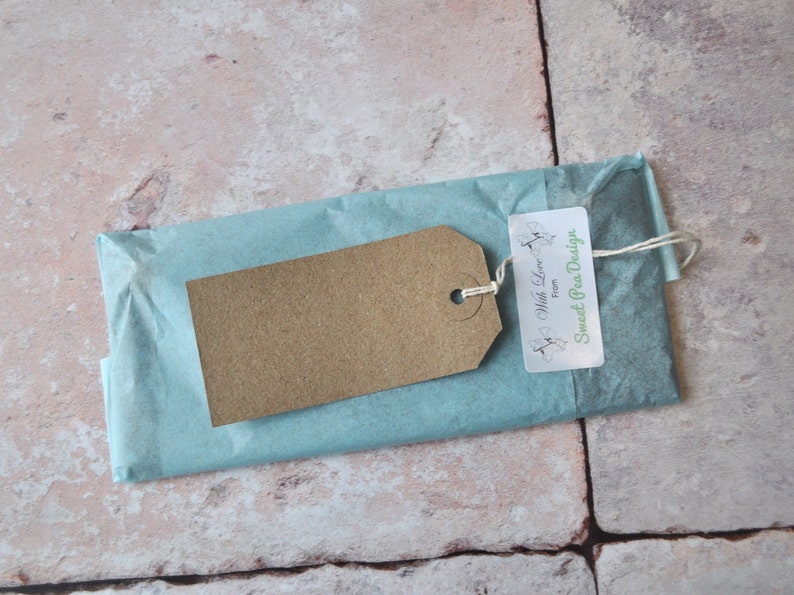 May include: A brown paper gift tag with the text "With Love from Sweet Pea Design" tied with twine to a light blue tissue paper package.