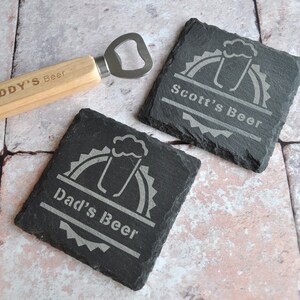 Puede incluir: Dos posavasos de pizarra negra con un gráfico de vaso de cerveza y el texto "Dad's Beer" y "Scott's Beer" en blanco. También se incluye un abridor de botellas de madera.