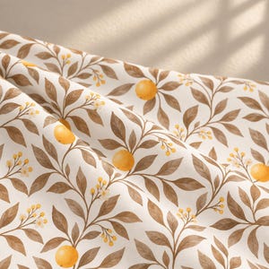 May include: A fabric featuring a repeating pattern of orange citrus fruits, small white flowers, and brown leaves on a cream-coloured background. The material is draped in soft folds, creating a textured appearance with light and shadow across the surface.