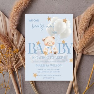Può includere: Un invito a un baby shower con sfondo azzurro chiaro, con un orsacchiotto che tiene dei palloncini. Il testo recita "We can bearly wait for BABY" e include i dettagli per l'arrivo di Jonathon, data, ora e informazioni RSVP.