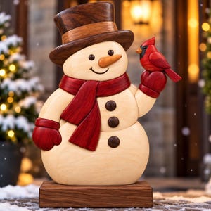 Op de afbeelding: Een houten sneeuwpopfiguur met een donkerbruine hoge hoed en een rode sjaal, voorzien van drie donkerbruine knopen en een wortelvormige neus. De sneeuwpop houdt een kleine rode kardinaalvogel op één hand, geplaatst op een rechthoekige voet.
