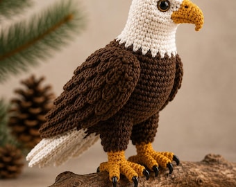 May include: A crocheted bald eagle figurine featuring a white head, dark brown body, and white tail feathers. The bird has a textured yellow beak, matching yellow feet with black claws, and dark brown eyes, standing in a profile position.