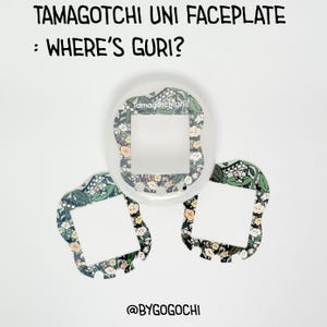 Op de afbeelding: Een doorzichtige Tamagotchi Uni-frontplaat met drie decoratieve frontplaten. De frontplaten hebben een bloemenpatroon met groene bladeren en gele en perzikbloemen. Tekst op de frontplaat luidt "TAMAGOTCHI UNI FACEPLATE : WHERE'S GURI?" en "@BYGOGOCHI".
