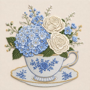 May include: An embroidery design featuring a white teacup and saucer with blue floral patterns, filled with a bouquet of blue hydrangea blossoms, two cream-colored roses, and small white and yellow accent flowers with green leaves.