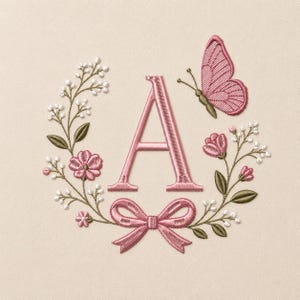 May include: An embroidered letter A in dusty pink, centered within a floral wreath featuring small white buds, pink blossoms, and green leaves. A pink butterfly is positioned at the top right, and a pink ribbon bow is centered at the bottom.