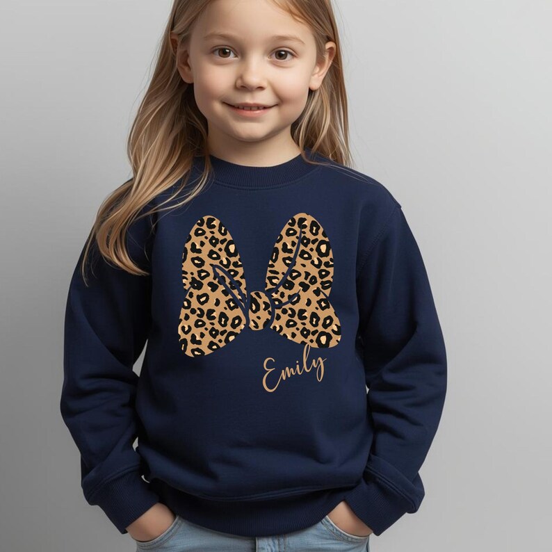 Op de afbeelding: Marineblauw sweatshirt met een grote strik met een luipaardprint. De strik staat in het midden van het sweatshirt. De naam "Emily" staat eronder in een sierlijk lettertype.